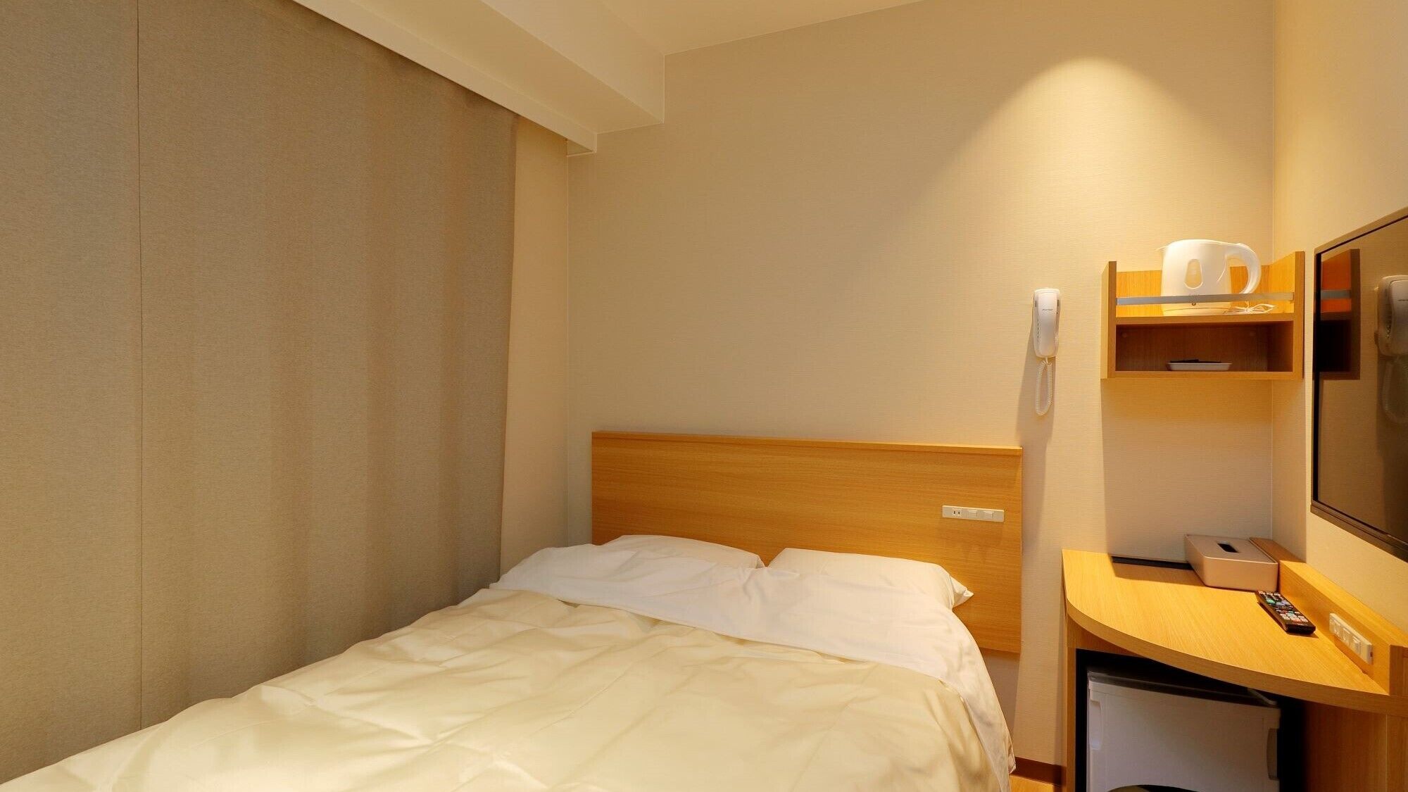 Een hotelkamer met een bed, een houten bureau, een telefoon en een televisie.