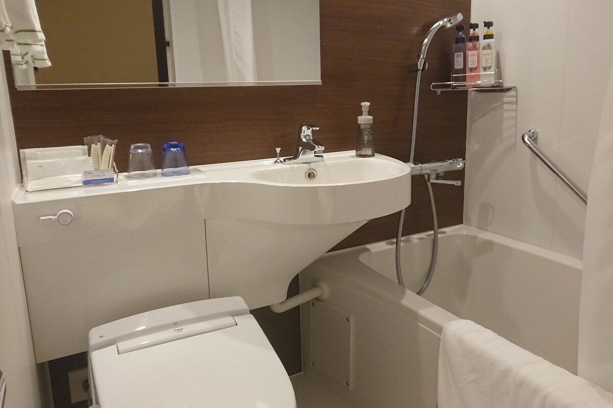 A bathroom with a white sink, a mirror, a toilet, and a shower.