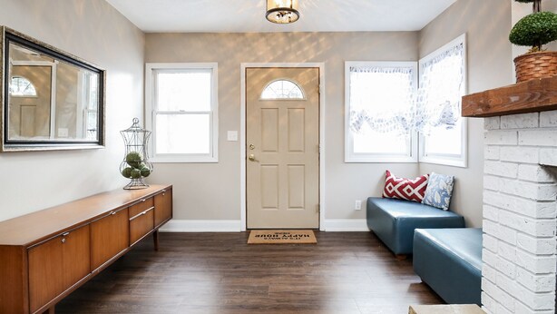 A hallway with a wooden bench, a door, and a wall-mounted mirror.