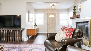 A living room with a leather sofa, a flat-screen TV, a fireplace, and a patterned rug.