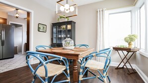 A dining area with a wooden table, blue chairs, a chandelier, and a cabinet with glass doors.