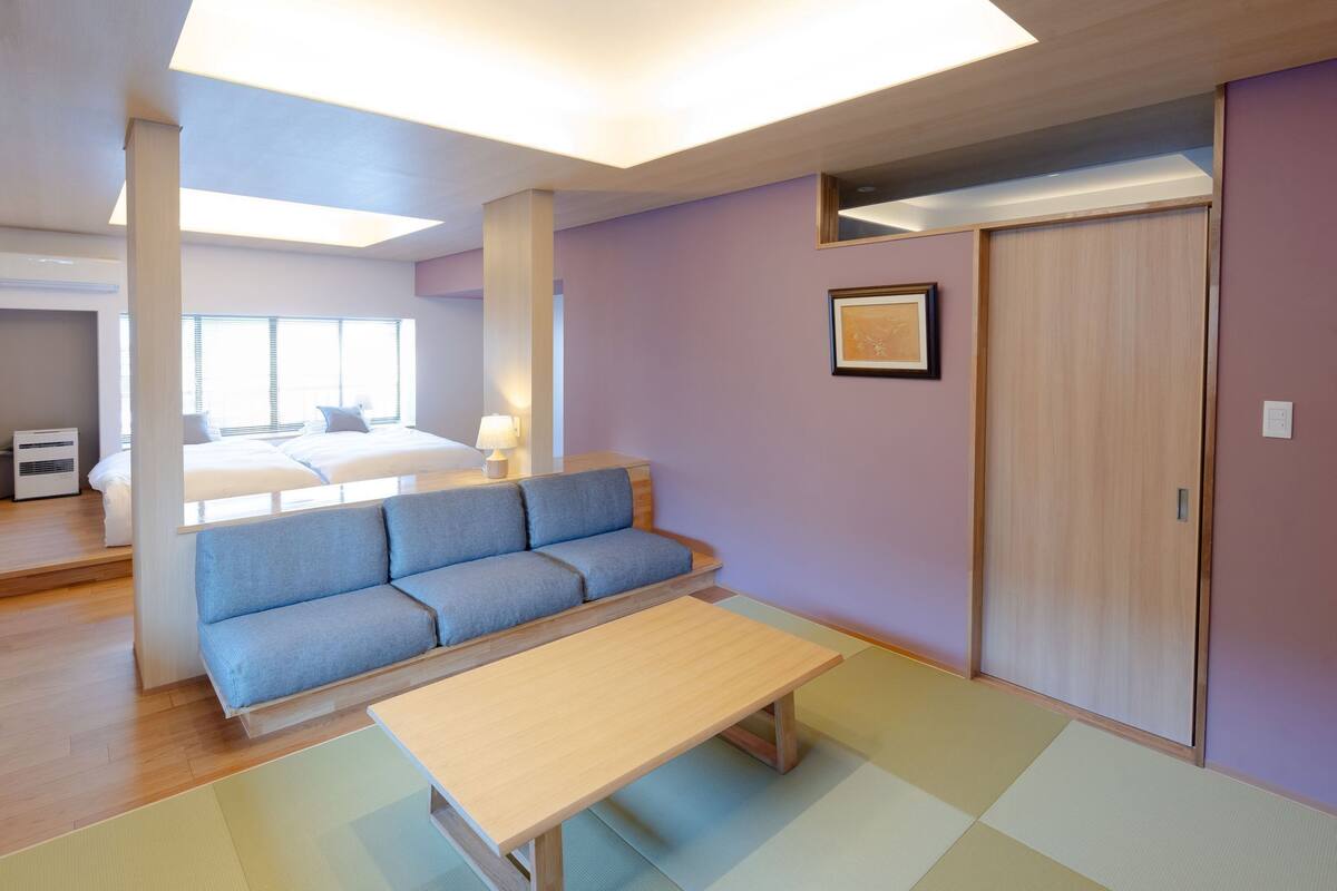 Quarto com sofá, mesa, cama e guarda-roupa.