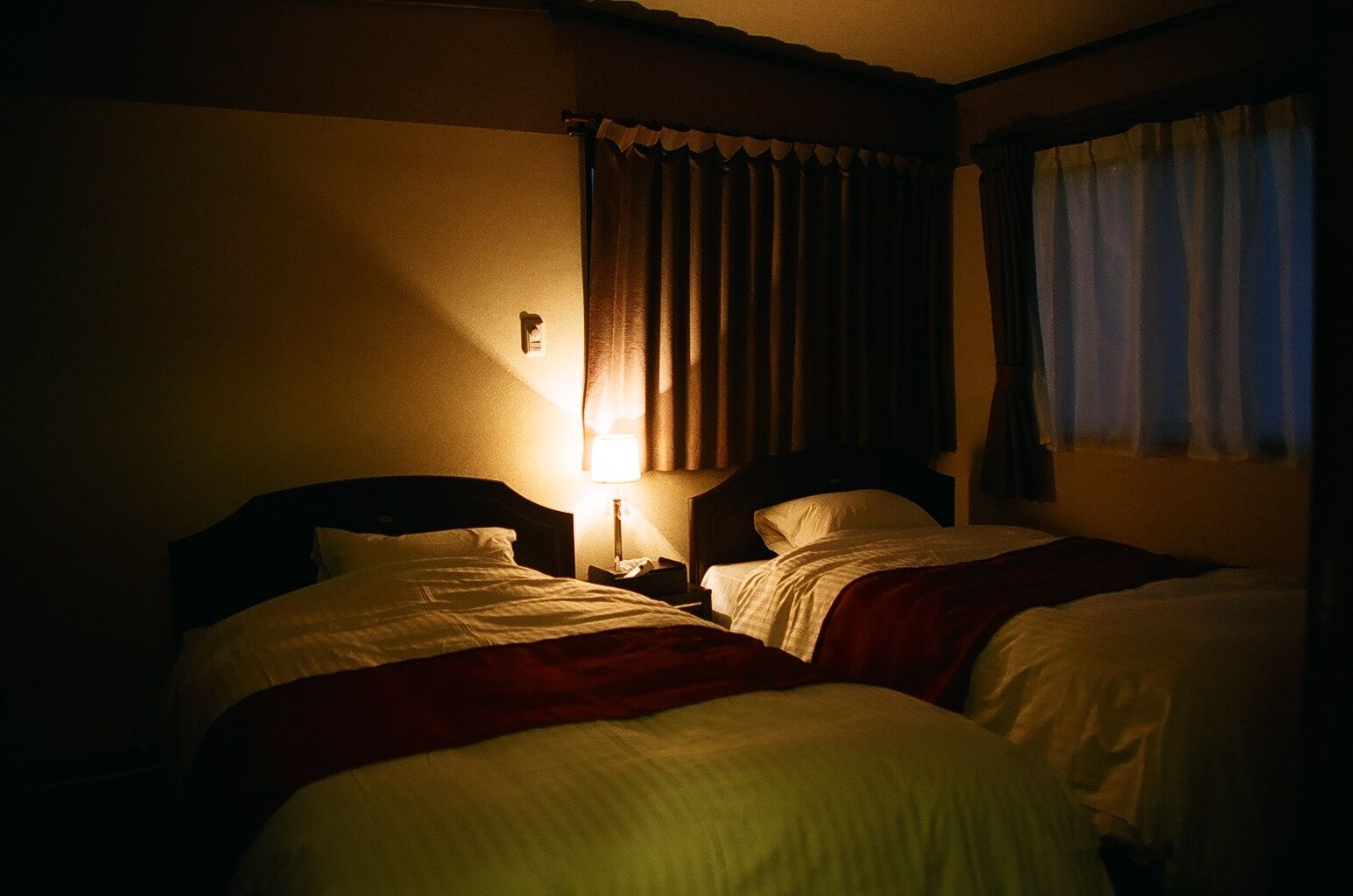 Una habitación de hotel con dos camas, una mesita de noche y una lámpara.