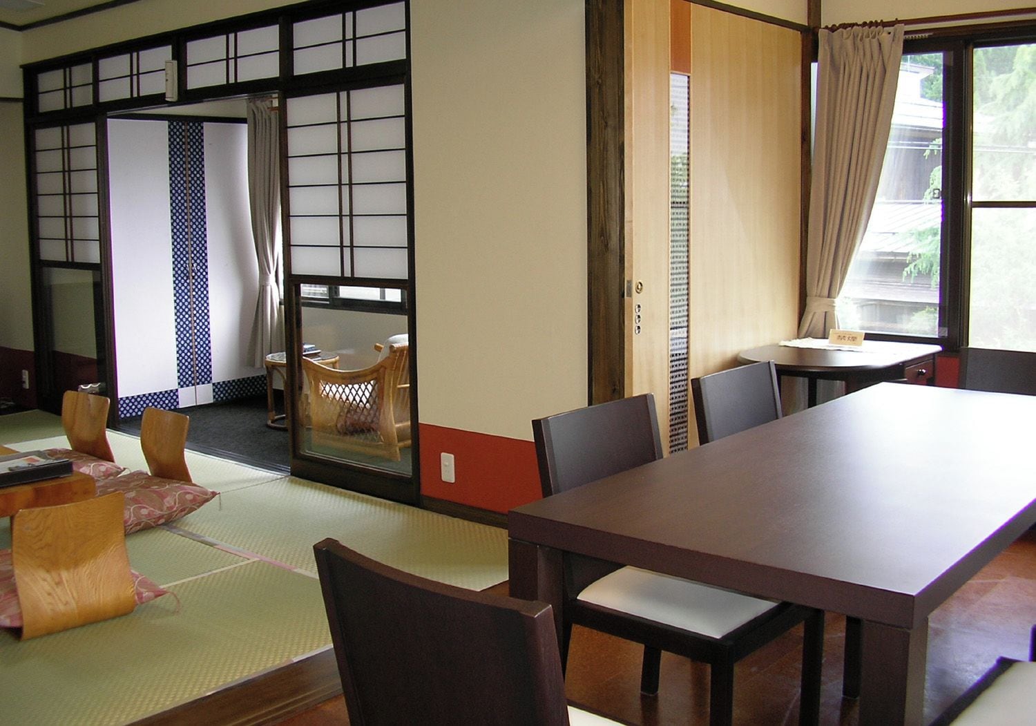 Una habitación tradicional japonesa con suelo de tatami, una mesa baja y puertas correderas.