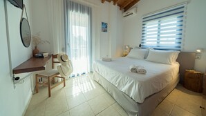 Een slaapkamer met een bed, een stoel, een bureau en een raam met zonwering.