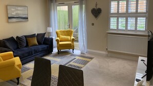 A living room with a blue sofa, a yellow armchair, and a patterned rug. -  Holiday rental in Rye, sleeps up to 6 with private gated driveway (Rye)