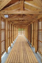 Un pasillo de madera con techo inclinado y ventanas grandes.