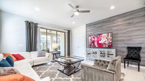 A modern living room with a sofa, armchair, coffee table, and a TV mounted on a wall. - 1min walk to New Community Pool, Luxury 7BD Home 19016 (Four Corners)
