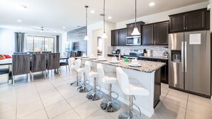 A modern kitchen with a central island, stainless steel appliances, and bar stools. - 1min walk to New Community Pool, Luxury 7BD Home 19016 (Four Corners)