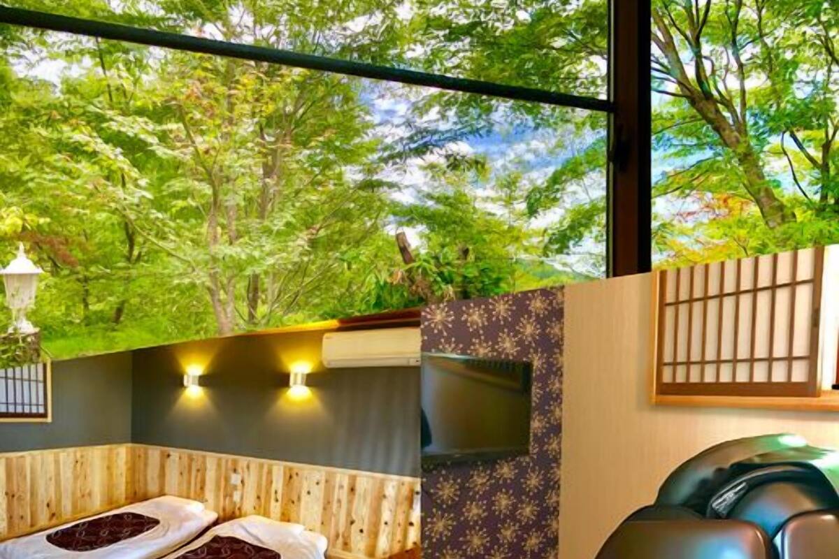A room with a wooden bench, a TV, and a view of trees.