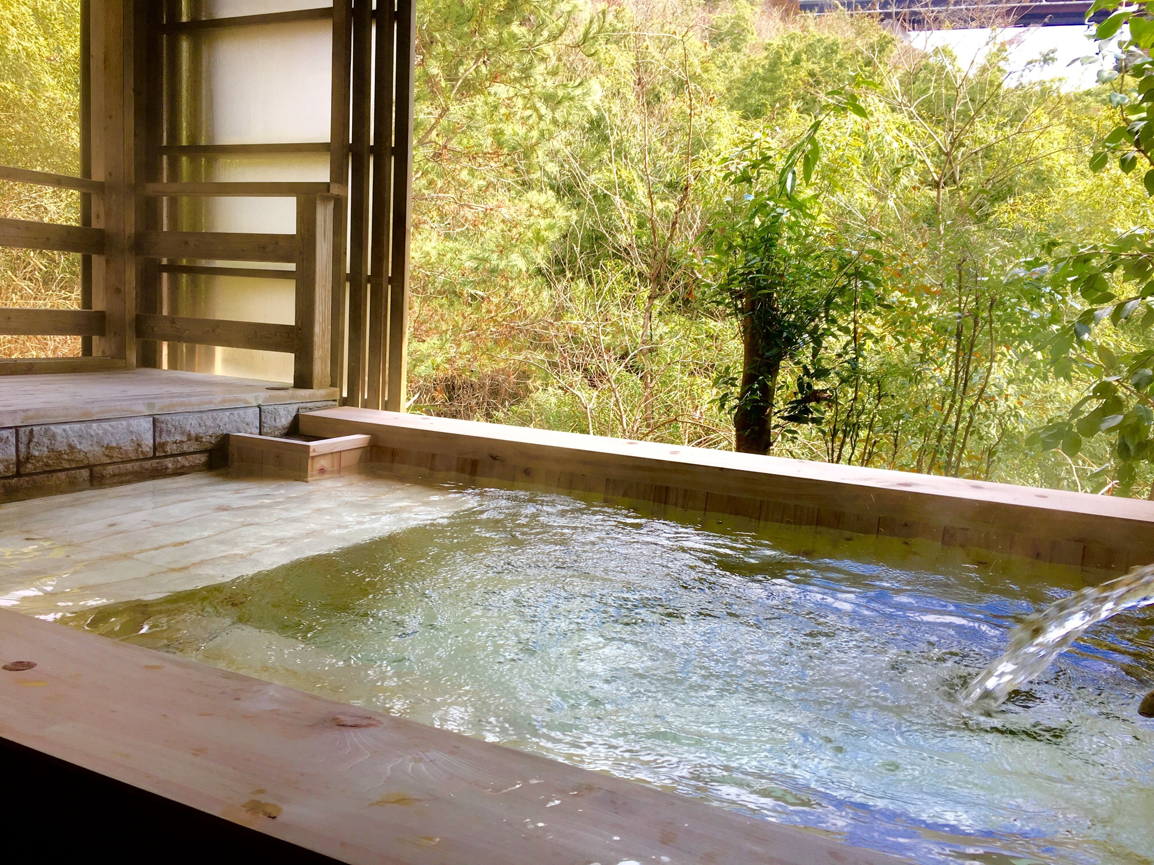 Un área de baños termales con una terraza de madera y escalones que bajan al agua.