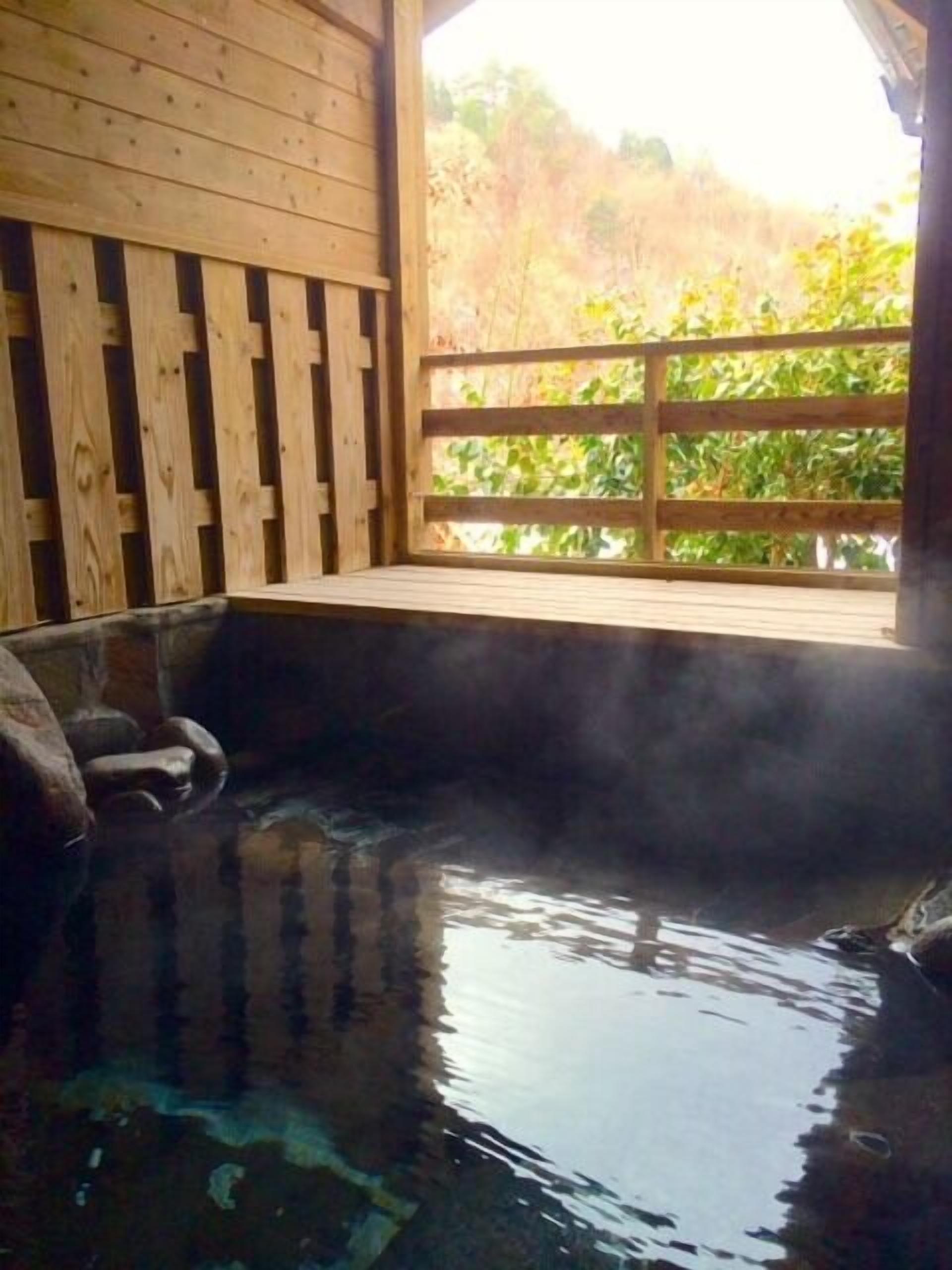 Ein Holz-Spa mit Thermalquelle, einer Holzterrasse und Blick auf Bäume.