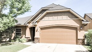 Een gelijkvloers huis met een beige gevel, een garage en een verzorgd gazon.