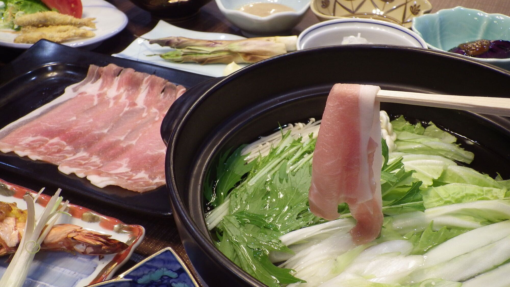 A hot pot with various ingredients like meat and vegetables.