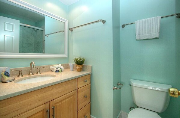 A bathroom with a sink, mirror, towel rack, toilet, and a potted plant.