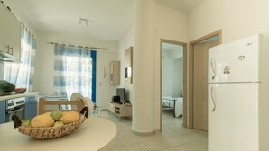 A modern kitchen with a dining table, a refrigerator, and a basket of fruit. - Sunset home crete 2 (Τρεις Εκκλησίες)