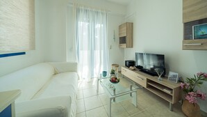 A modern living room with a sofa, glass coffee table, TV stand, and a decorative plant. - Sunset home crete 2 (Τρεις Εκκλησίες)