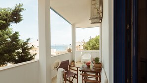 A balcony with a view of the sea, a table with chairs, and a potted plant. - Sunset home crete 2 (Τρεις Εκκλησίες)