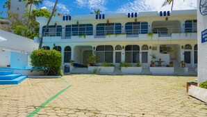 A courtyard with a paved floor, a staircase leading to a balcony, and a building with multiple windows and balconies. - Suites La Audiencia (Manzanillo)