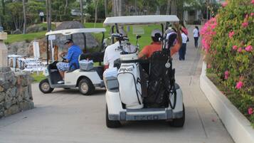 A golf cart with golf clubs and a Ping golf bag.