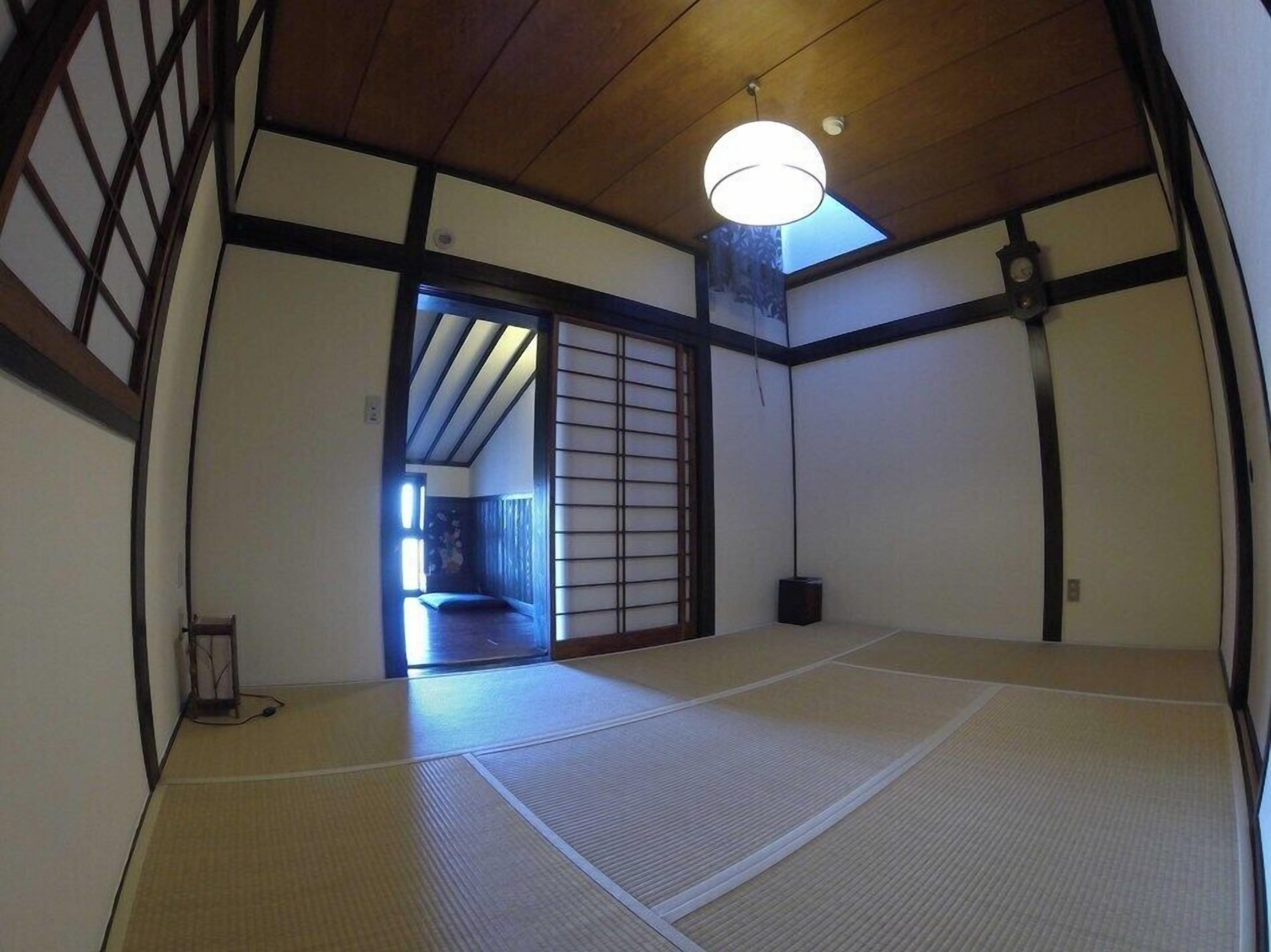 Habitació japonesa tradicional amb fons de tatami, una porta penjant de tipus shoji i un llum penjant.