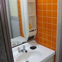 A bathroom with a white sink, a mirror, and orange tiled walls.