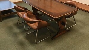 Ein Konferenzraum mit einem Holztisch, sechs Stühlen, einem Fernseher und einer Schiebetür.