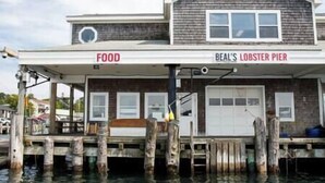 Ein zweistöckiges Gebäude mit einem Schild mit der Aufschrift „BEAL'S LOBSTER PIER“ und einem weiteren Schild, das einen Gastronomiebereich kennzeichnet.