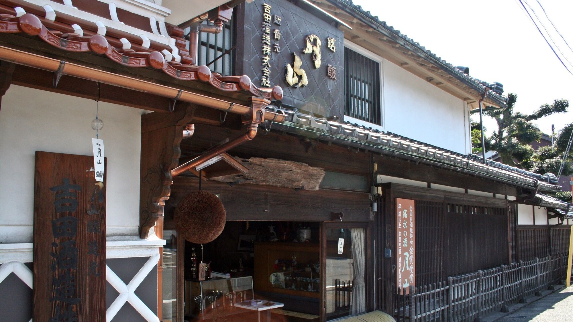 Un bâtiment japonais traditionnel, doté d’une façade en bois, d’une enseigne noire avec des caractères dorés et d’une devanture visible.