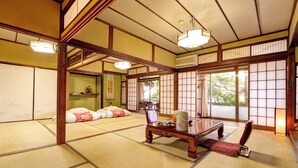 Una habitación japonesa tradicional con suelo de tatami, puertas correderas y una baja mesa de madera con cojín.