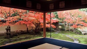Una habitación japonesa tradicional con suelo de tatami, vistas a flores de cerezo y un farol.