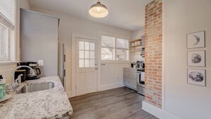 Eine Küche mit einer Granit-Arbeitsplatte, einem Spülbecken, einem Kühlschrank und einer Wand mit Ziegeln.