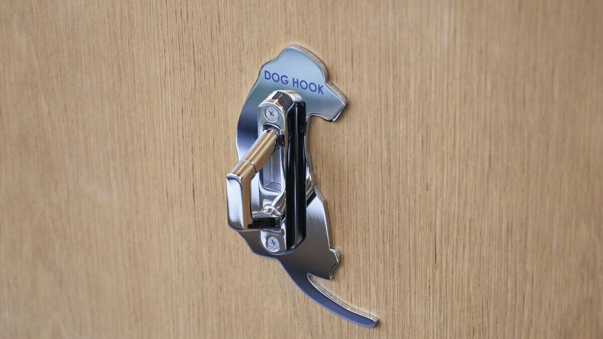 A metal dog hook on a wooden door.