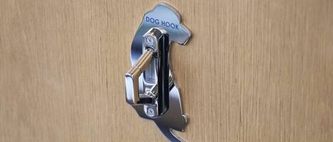 A metal dog hook on a wooden door.