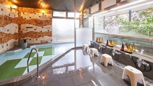 Un área de piscina interior moderna con una pared de vidrio transparente, una zona de estar con taburetes y un bar con diversas botellas.