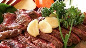 A wooden cutting board with sliced beef, carrots, potatoes, and parsley. - Awaji TT House II Pacific Over Seas (Sumoto)