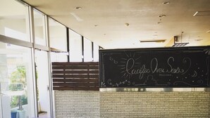 A cafe interior with a chalkboard menu, wooden tables, and a brick wall. - Awaji TT House II Pacific Over Seas (Sumoto)