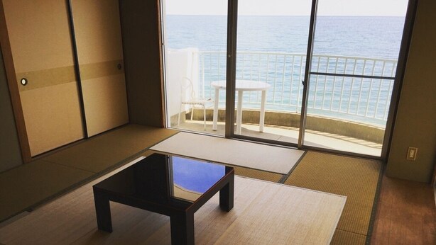 A room with tatami flooring, a low table, and a view of the sea through a sliding door. - Awaji TT House II Pacific Over Seas (Sumoto)