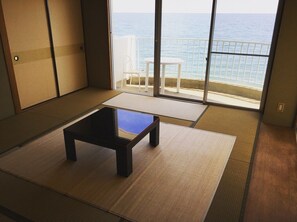 A room with tatami flooring, a low table, and a view of the sea through a sliding door. - Awaji TT House II Pacific Over Seas (Sumoto)