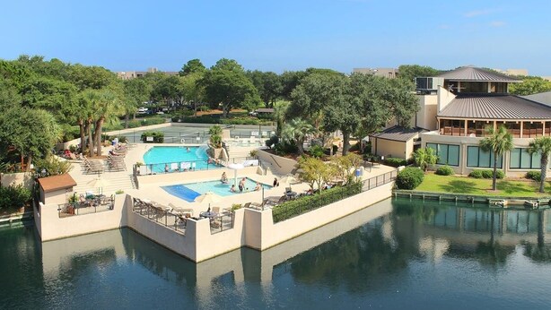 Um resort com uma grande área de piscina, uma piscina separada e um edifício com telhado inclinado.