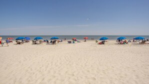 Uma praia com vários guarda-sóis e espreguiçadeiras.