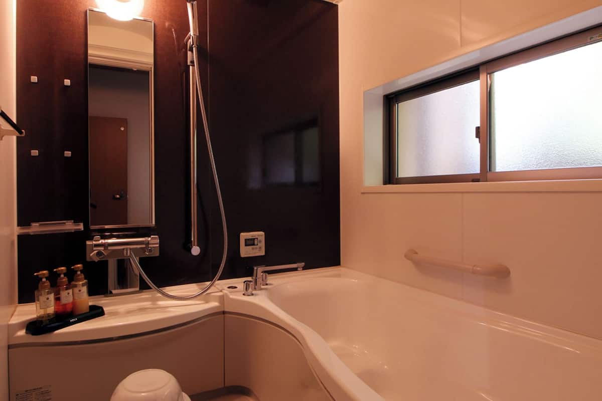 A bathroom with a bathtub, a shower, a toilet, and a window.