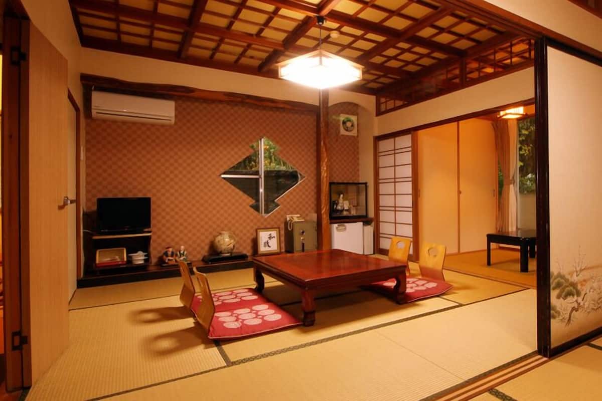 A traditional Japanese room with tatami flooring, a low table, a television, and sliding doors.