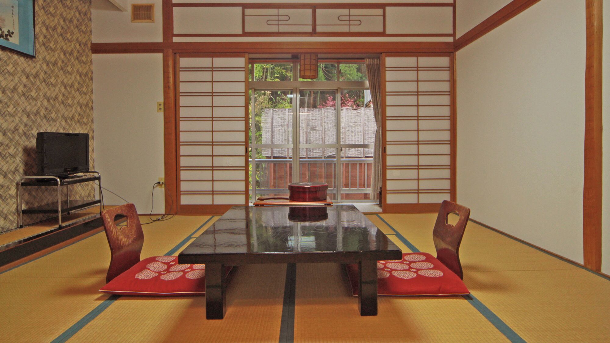 Una habitación tradicional japonesa con suelo de tatami, una mesa baja y puertas correderas shoji.