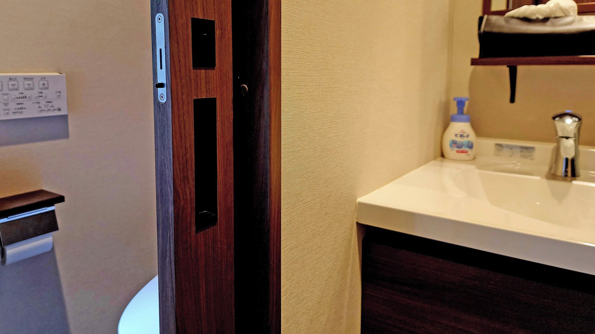 Un baño con un lavamanos blanco, una botella de jabón para manos y un perchero para toallas.