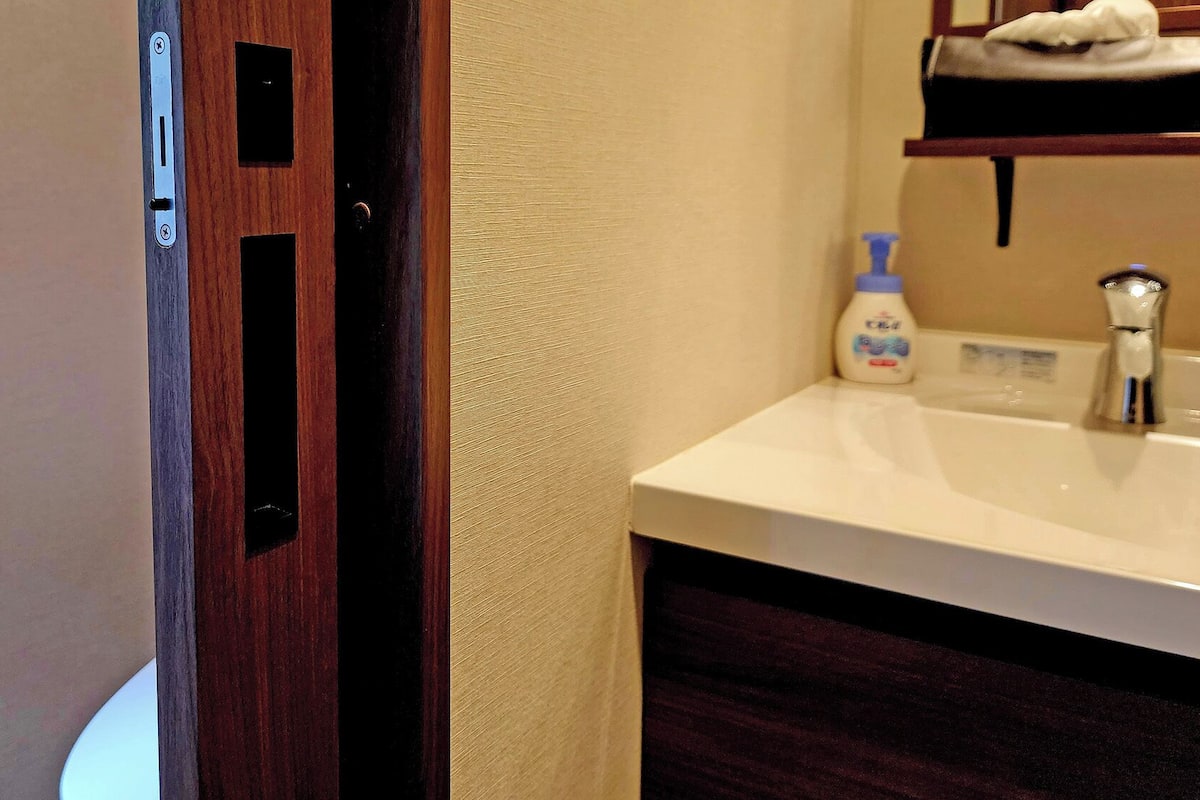A bathroom with a white sink, a bottle of hand soap, and a towel rack.
