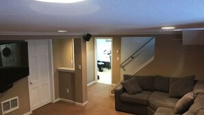 A living room with a sectional sofa, a flat-screen TV mounted on the wall, and a staircase leading to another level. - Fulton Retreat - Downtown Minneapolis - 50th and France! (Minneapolis)