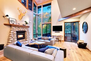 Una sala moderna con chimenea de piedra, ventanas amplias y un rincón de descanso acogedor.