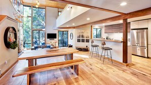 Eine geräumige Küche mit einer großen Kochinsel, Holzböden und einem modernen, edlen Kühlschrank aus Edelstahl.