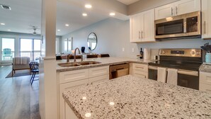 A modern kitchen with granite countertops, stainless steel appliances, and white cabinetry. - Ramsgate 22 | Renovated Gulf-Front Escape (Panama City Beach)